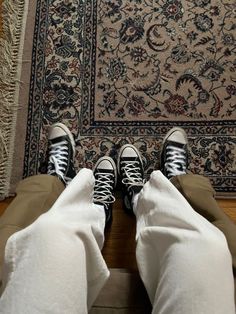 two people standing in front of a rug with their feet up on the floor and one person wearing sneakers