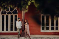 a man and woman standing next to each other in front of a red brick building