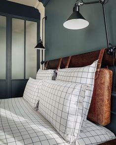 a bed with white and black sheets in a bedroom next to a wall mounted lamp