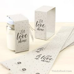 some paper tags are sitting next to a jar and candle on a table with the words let love shine printed on them