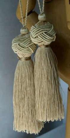 two tassels are hanging from the back of a wooden chair with ropes attached to it