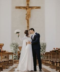 a bride and groom standing in front of a cross