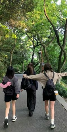 three girls are walking down the street with backpacks on