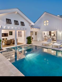 a house with a swimming pool in front of it and an outdoor lounge area next to the pool