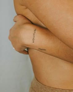 a person with a small tattoo on their left arm and the word written in cursive writing