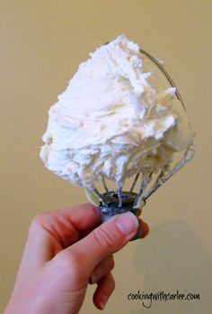 a hand holding a wire whisk filled with whipped cream