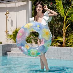 a woman holding an inflatable flowered ring around her neck standing in a pool