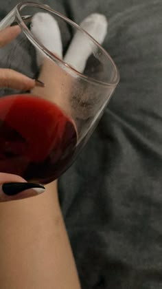 a woman holding a wine glass with red liquid in it