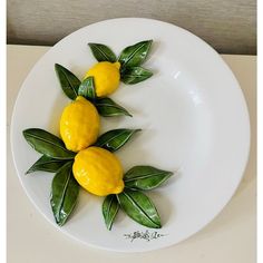 two lemons with green leaves on a white plate