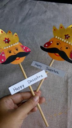 two handmade masks on sticks with happy dusse written on them