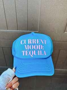 This blue foam and mesh trucker hat features a vibrant pink font graphic that says "current mood: tequila." Perfect for any tequila lover, this fun and stylish hat will keep you looking cool and feeling confident. Made with high-quality materials, this trucker hat is sure to make a statement at any event or outing. Fun Blue Trucker Hat With Letter Print, Keep On Truckin, Font Graphic, Feeling Confident, Hat Ideas, Vintage Couture, Stylish Hats, Current Mood, Band Tees