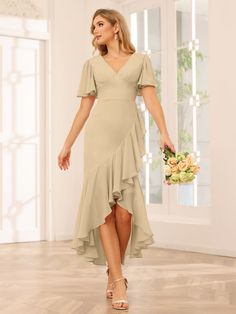 a woman in a beige dress is holding a bouquet and standing on a wooden floor