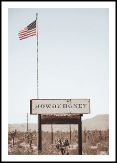 an american flag flying over the bowdy huney sign in front of a desert landscape