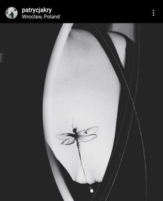 a black and white photo of a woman's stomach with a dragonfly tattoo on it