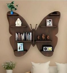 a butterfly shaped shelf with books and pictures on it