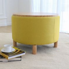 a yellow ottoman sitting on top of a rug next to a cup and saucer