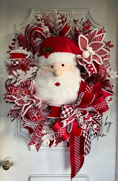 a christmas wreath with a santa clause on the front door and red ribbon around it