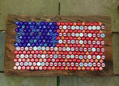 an american flag made out of beer cans is displayed on a wooden plank outside in front of a brick wall