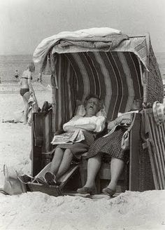 an old photo of two people sitting in a beach chair