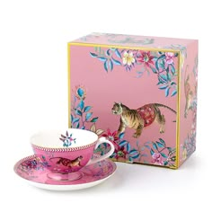 a pink tea cup and saucer in front of a box with an image of a tiger on it