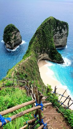 stairs leading down to the beach with two large rock formations in the water behind them