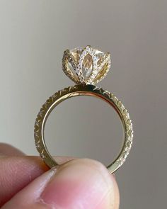 a hand holding a yellow and white ring with a diamond in it's center