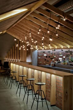 an indoor bar with stools and lights hanging from the rafter ceiling above it