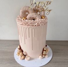 a birthday cake decorated with pink frosting and gold decorations