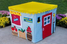 a child's play house in the shape of a school building with flowers around it