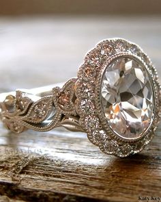 a close up of a ring on top of a wooden table with a diamond in the center