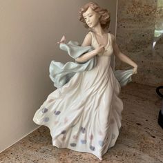 a ceramic figurine is standing on the counter in front of a wall with a vase