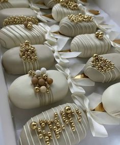 some white and gold decorated chocolates are on display in a box with ribbons around them