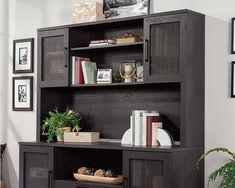 a black bookcase with books and pictures on the wall