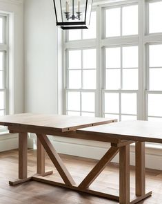 a wooden table sitting in front of two windows with candles on top of the table