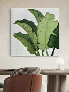 a large green plant on a white wall above a wooden table