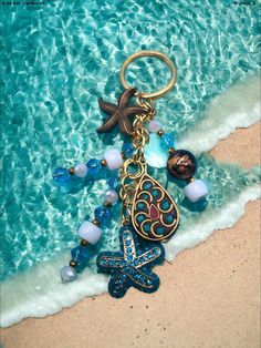 a close up of a keychain on the beach with a starfish and beads