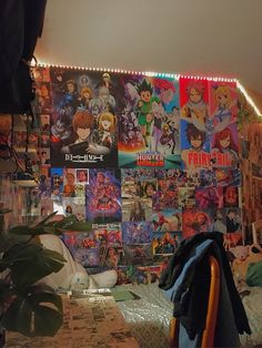 a room with posters on the wall and plants in the corner next to the bed