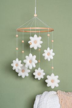 a baby crib mobile with white flowers hanging from it's sides and wooden beads