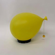 a yellow object with a black base and a string attached to the top of it