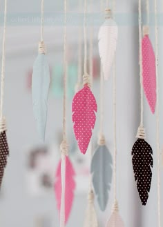 several different colored feathers hanging from a string in a room with polka dots on them