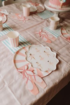 the table is set with pink and blue striped paper plates, cups, and napkins