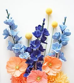 an arrangement of colorful flowers on a white background with blue and orange flowers in the center