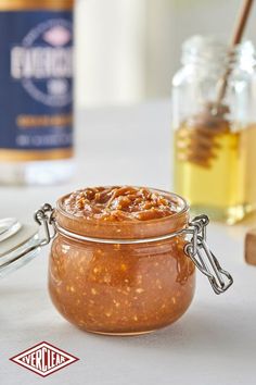 a jar filled with honey sitting on top of a table next to spoons and jars