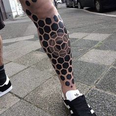 a man's leg with black and grey honeycombs tattoo on the legs