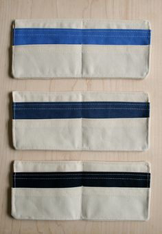 three pieces of cloth with blue and white stripes on them sitting on a wooden surface