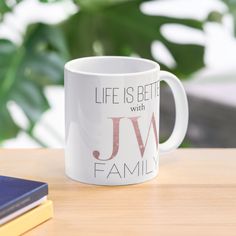 a white coffee mug sitting on top of a wooden table next to a blue book