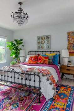 a bed room with a neatly made bed and lots of colorful rugs on the floor