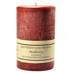 a red candle that is sitting on a white surface with the words, texturesd coronade mulberry