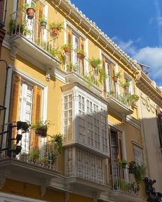 an apartment building with many windows and plants on the balconies