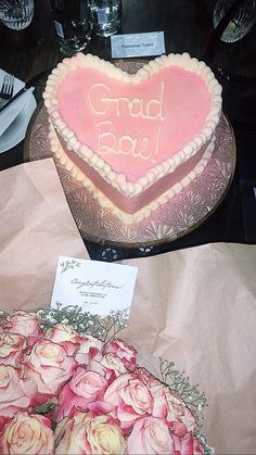 a heart shaped cake sitting on top of a table next to paper bags and flowers